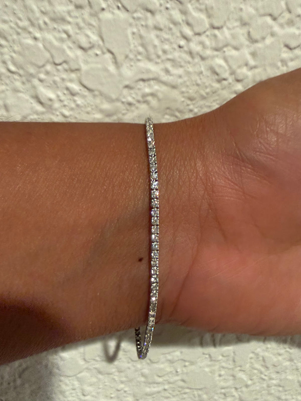 Lab diamond tennis bracelet catching daylight, round brilliant stones in white gold