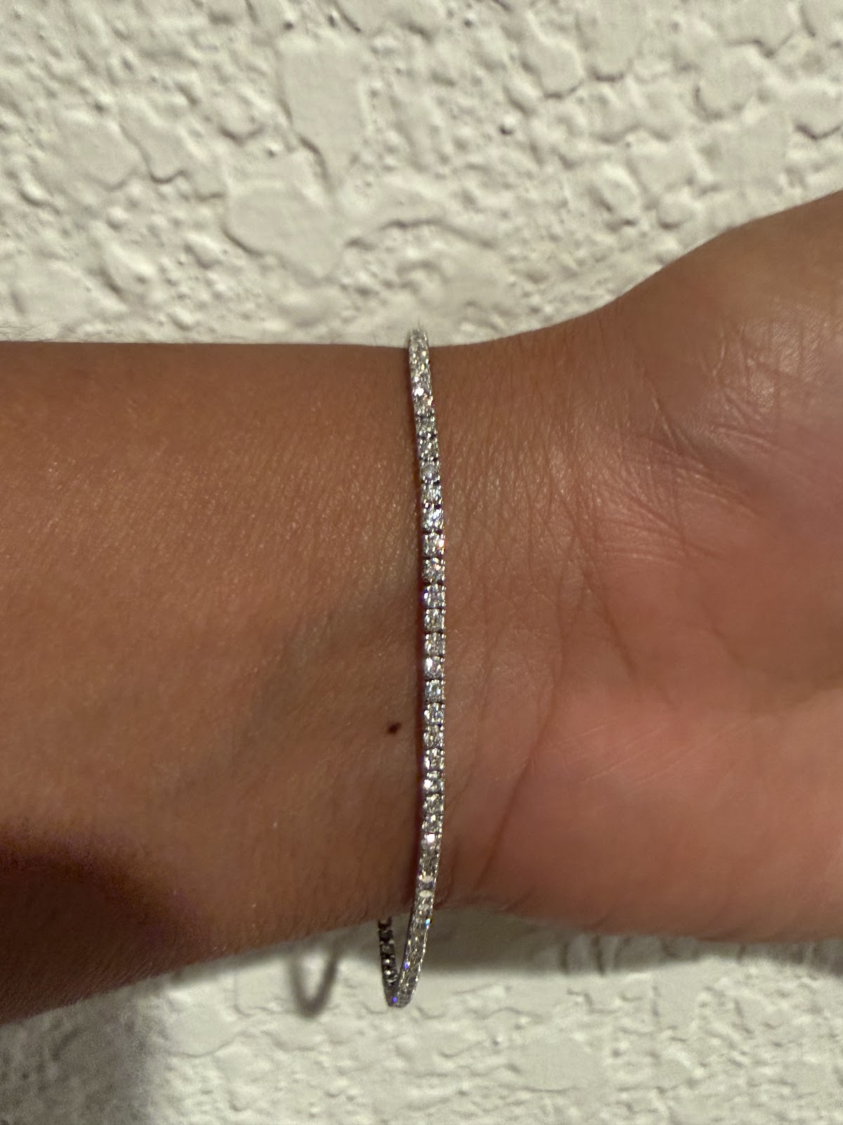 Lab diamond tennis bracelet catching daylight, round brilliant stones in white gold